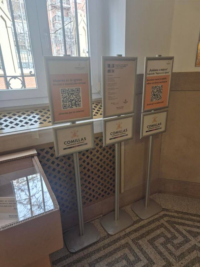 Paneles informativos en un edificio con códigos QR y referencias a Comillas.