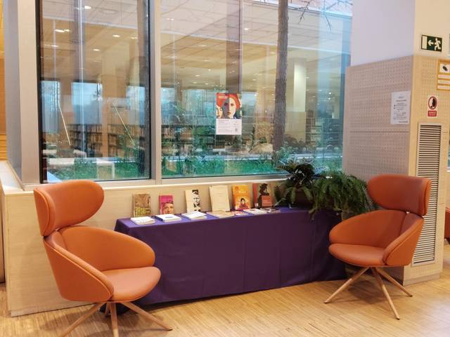 Espacio de lectura que incluye una mesa con libros y sillones cómodos.