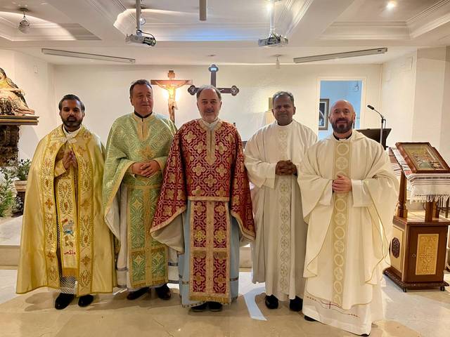 Un grupo de cinco personas vestidas con túnicas religiosas en un entorno eclesiástico.