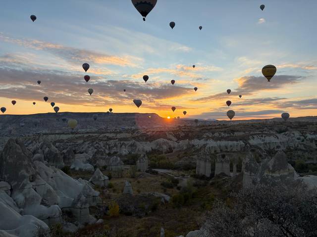 Un hermoso paisaje al amanecer con muchos globos aerostáticos en el cielo.