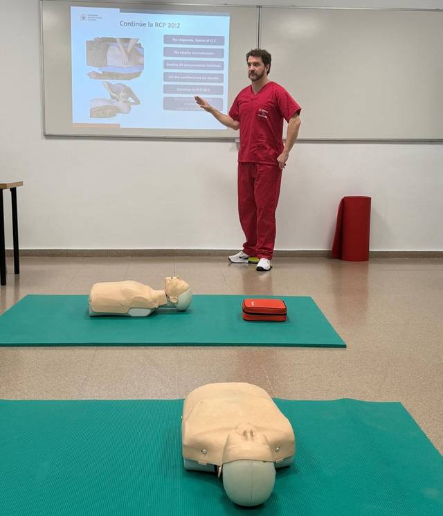 Un instructor de RCP enseña a un grupo utilizando maniquíes en un aula de primeros auxilios.