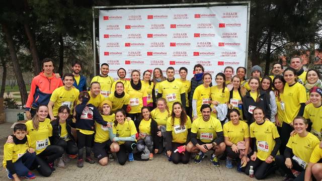 A group of people in athletic wear posing for a photo at a running event in front of a banner with logos.