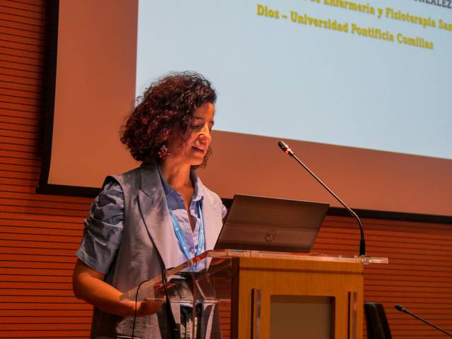 Una mujer está presentando en una conferencia frente a un podio con una computadora portátil.