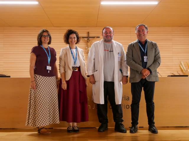 Cuatro personas posan juntas en un evento formal con un fondo de panel de madera.