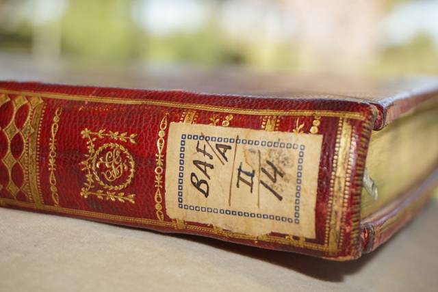 Un libro antiguo con un lomo de cuero rojo y una etiqueta en la portada.