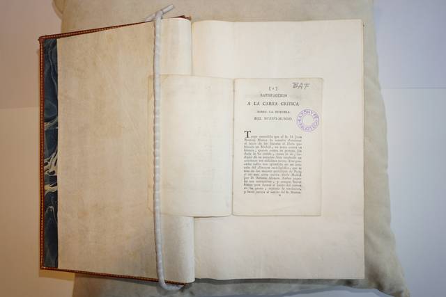 Una página de un libro abierto que muestra un texto impreso y un sello.