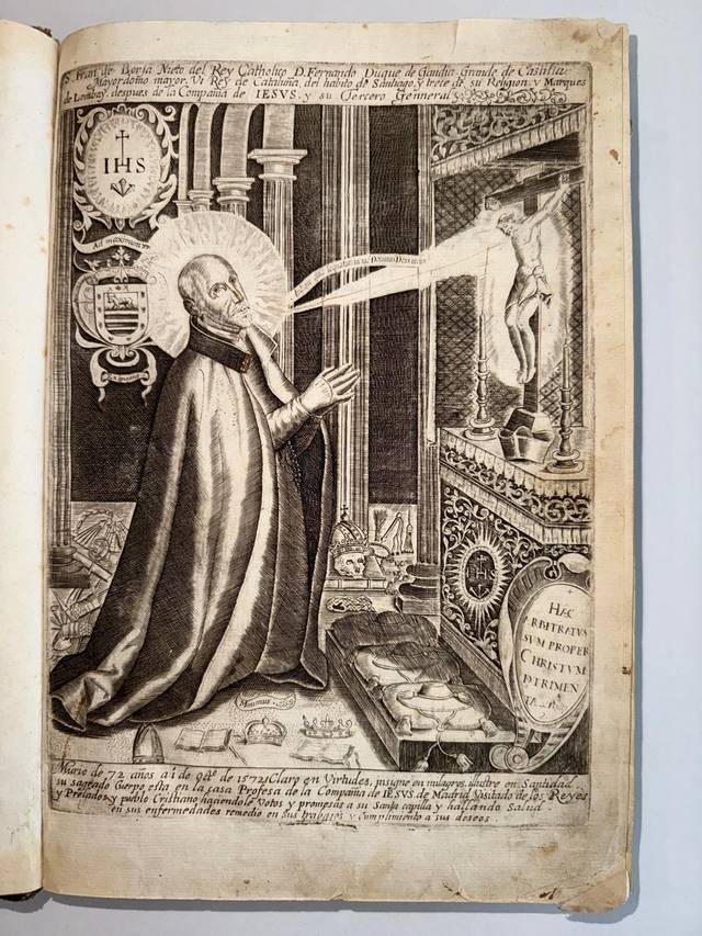 La imagen muestra a un santo rezando con una figura sagrada en el fondo.