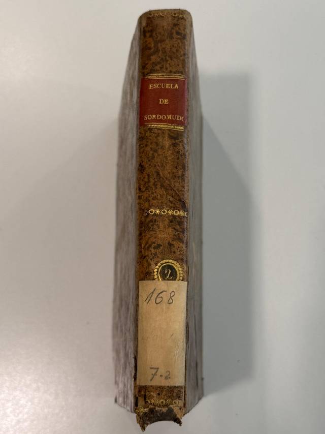 Un libro antiguo titulado 'Escuela de Sordomudos' con un lomo desgastado.