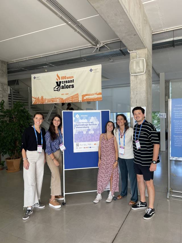 Five people standing in front of a conference poster, smiling for the camera.