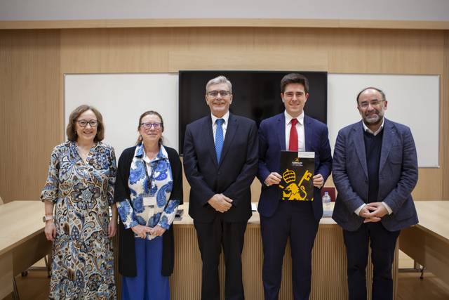Grupo de personas posando en una sala con una presentación en curso.