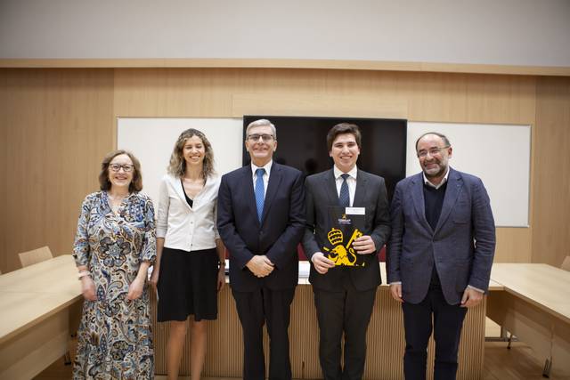 Un grupo de cinco personas se encuentra de pie en una sala moderna, sonriendo y posando para la foto.