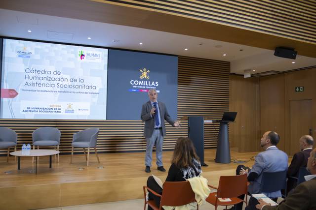 Un ponente presenta un tema sobre la humanización de la asistencia sociosanitaria en un auditorio moderno.