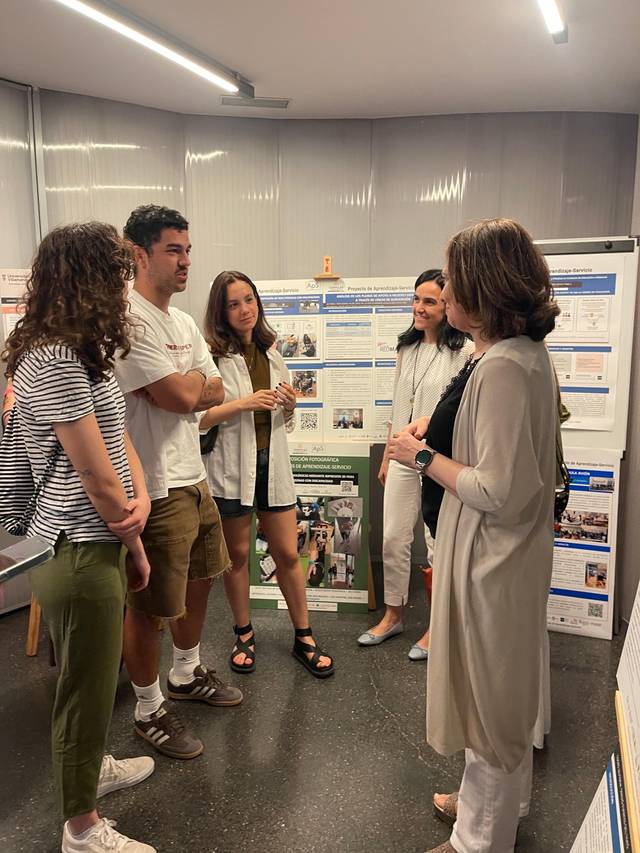 Un grupo de personas discute frente a carteles informativos en un evento académico.