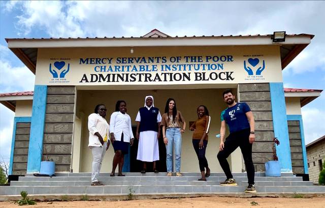A group of people standing in front of the Mercy Servants of the Poor Charitable Institution Administration Block building.