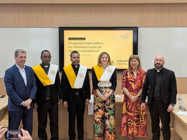 Un grupo de cinco personas posan en un evento de graduación con togas y medallas en un entorno académico.