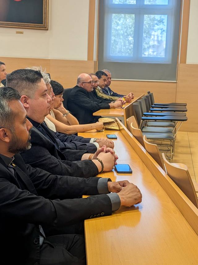 Un grupo de personas sentadas en una sala, prestando atención durante un evento.