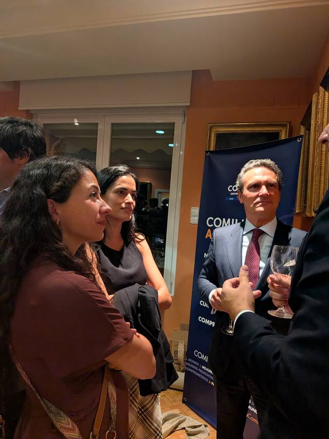 Un grupo de personas conversando en un evento social mientras sostienen copas.