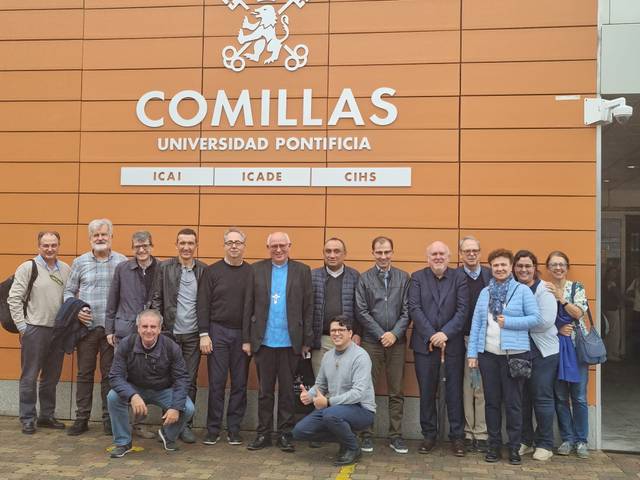 A group of people posing in front of the Comillas Pontifical University sign