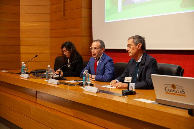 Three professionals sitting at a panel discussion table in a conference room.