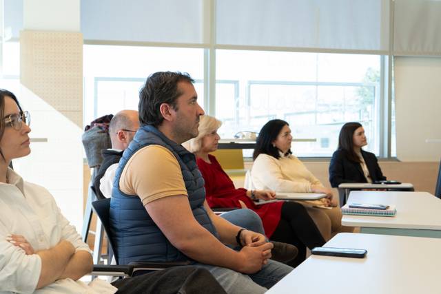 Un grupo de personas escuchando atentamente durante una presentación en un aula.