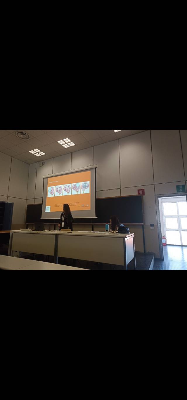 Una persona presenta un tema en una sala de conferencias con una proyección en la pantalla.