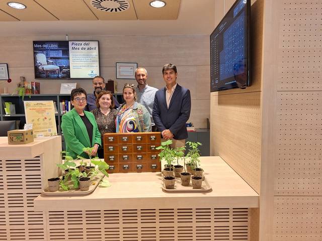 Un grupo de seis personas posando sonrientes en una oficina, rodeados de plantas en macetas.