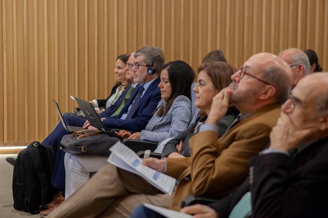 Un grupo de personas sentadas en una conferencia prestando atención.