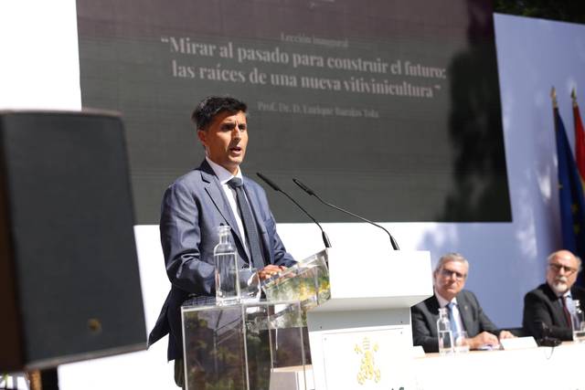 Un hombre habla en un evento sobre viticultura mientras una audiencia lo escucha atentamente.