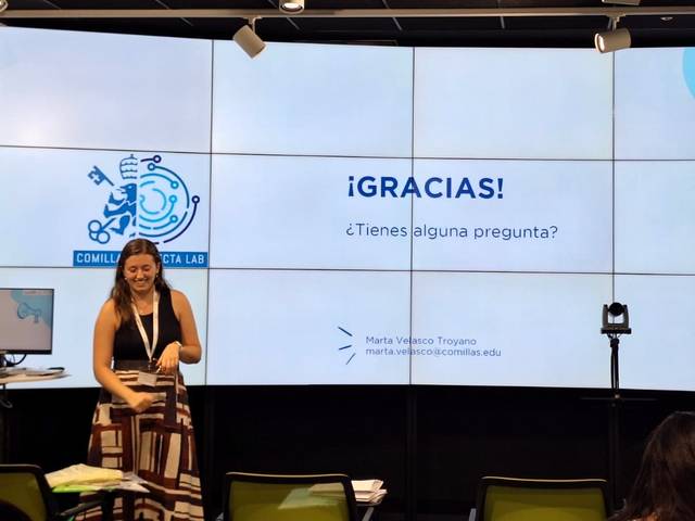Una mujer presenta en una conferencia con una pantalla detrás que dice '¡GRACIAS! ¿Tienes alguna pregunta?'