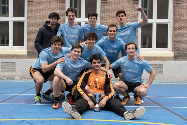 Un grupo de jóvenes jugadores de fútbol celebran su victoria sosteniendo un trofeo.