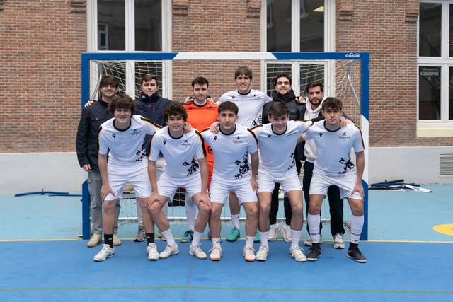 Un grupo de jóvenes futbolistas posando en equipo frente a una portería en una cancha.