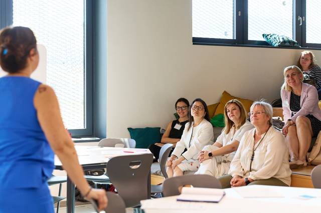 Un grupo de mujeres observa a una presentadora en un entorno de trabajo colaborativo.