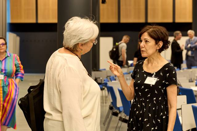 Dos mujeres conversan apasionadamente en un evento.