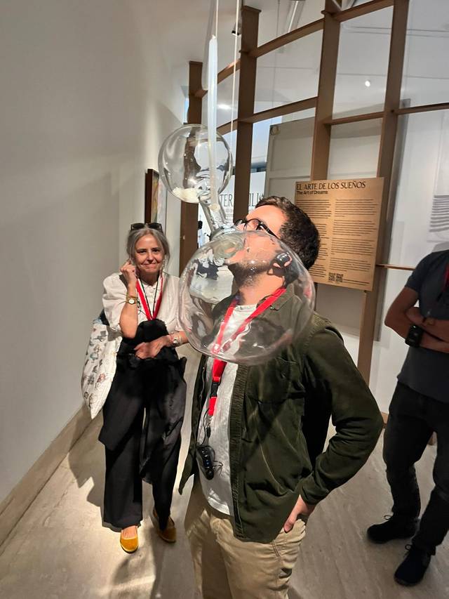 Una exposición artística donde un hombre interactúa con burbujas en un museo.