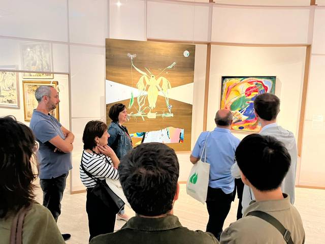 Un grupo de personas observa dos obras de arte en una galería.