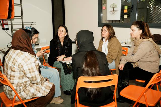 Un grupo de mujeres sentadas en círculo en un ambiente de trabajo colaborativo.