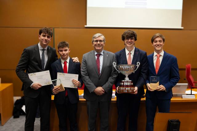 Cinco hombres de pie en una sala, sosteniendo premios y sonriendo a la cámara.