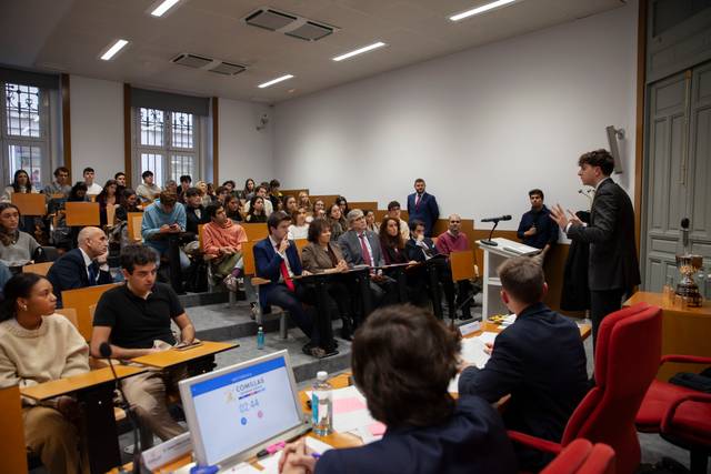 Un hombre está dando una presentación frente a un grupo de personas sentadas en un aula.