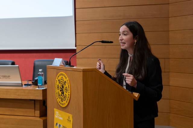 Una mujer habla en un podio mientras presenta en un evento.
