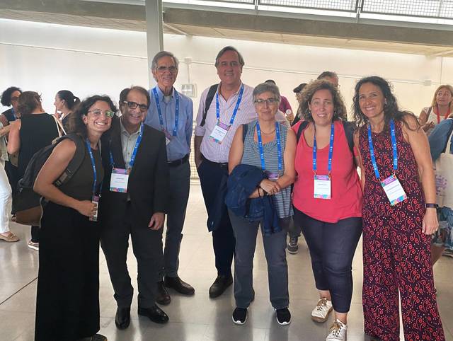 A group of seven people wearing lanyards and smiling indoors at a conference event.