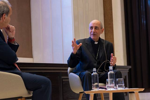 Un hombre con vestimenta religiosa está participando en una conversación en un evento.