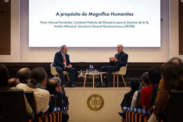 Un evento donde dos ponentes discuten sobre 'Magnífica Humanitas' frente a una audiencia.