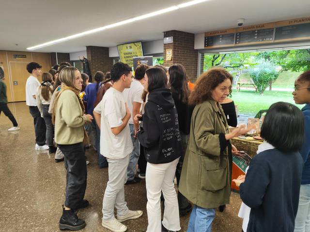 A group of people of various ages standing and interacting at an indoor book stall.