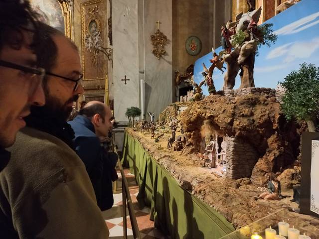 Personas observan un belén tradicional dispuesto en el interior de una iglesia.