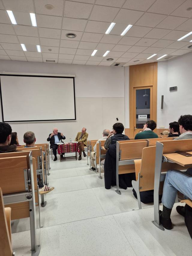 Personas asistiendo a una conferencia en un aula universitaria.