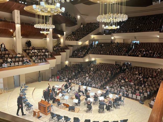 Un auditorio lleno de público contempla a una orquesta en el escenario.