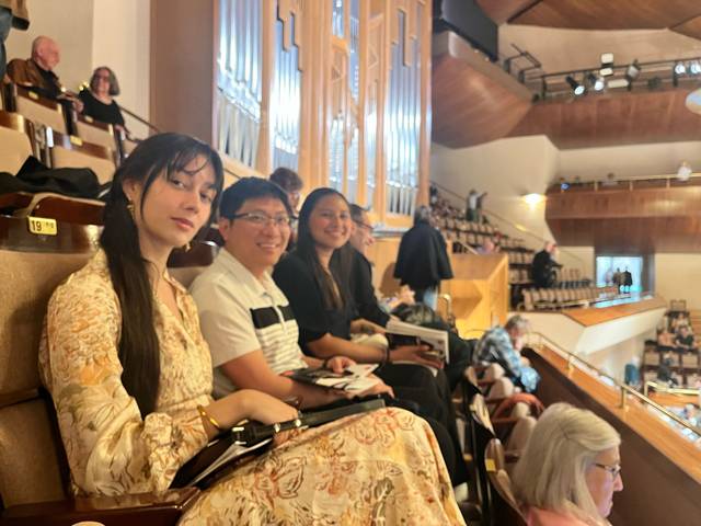 Un grupo de personas sentadas en un auditorio, disfrutando de un evento.