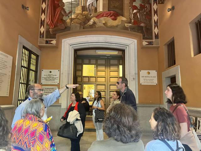 Un grupo de personas escucha atentamente a un guía turístico en un edificio histórico.