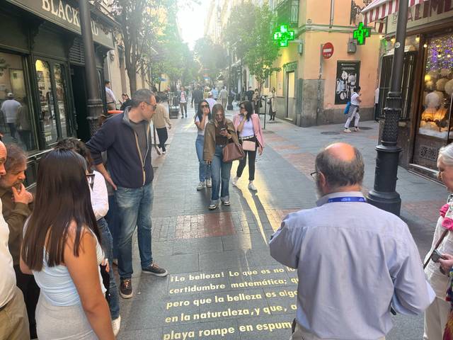 Un grupo de personas observa un texto en la calle que habla sobre la belleza y las matemáticas.