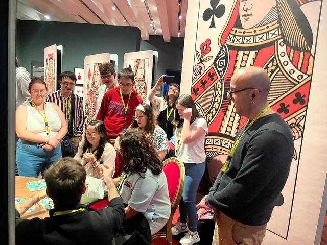 Un grupo de personas observa atentamente a un presentador en una actividad relacionada con cartas en un ambiente creativo.